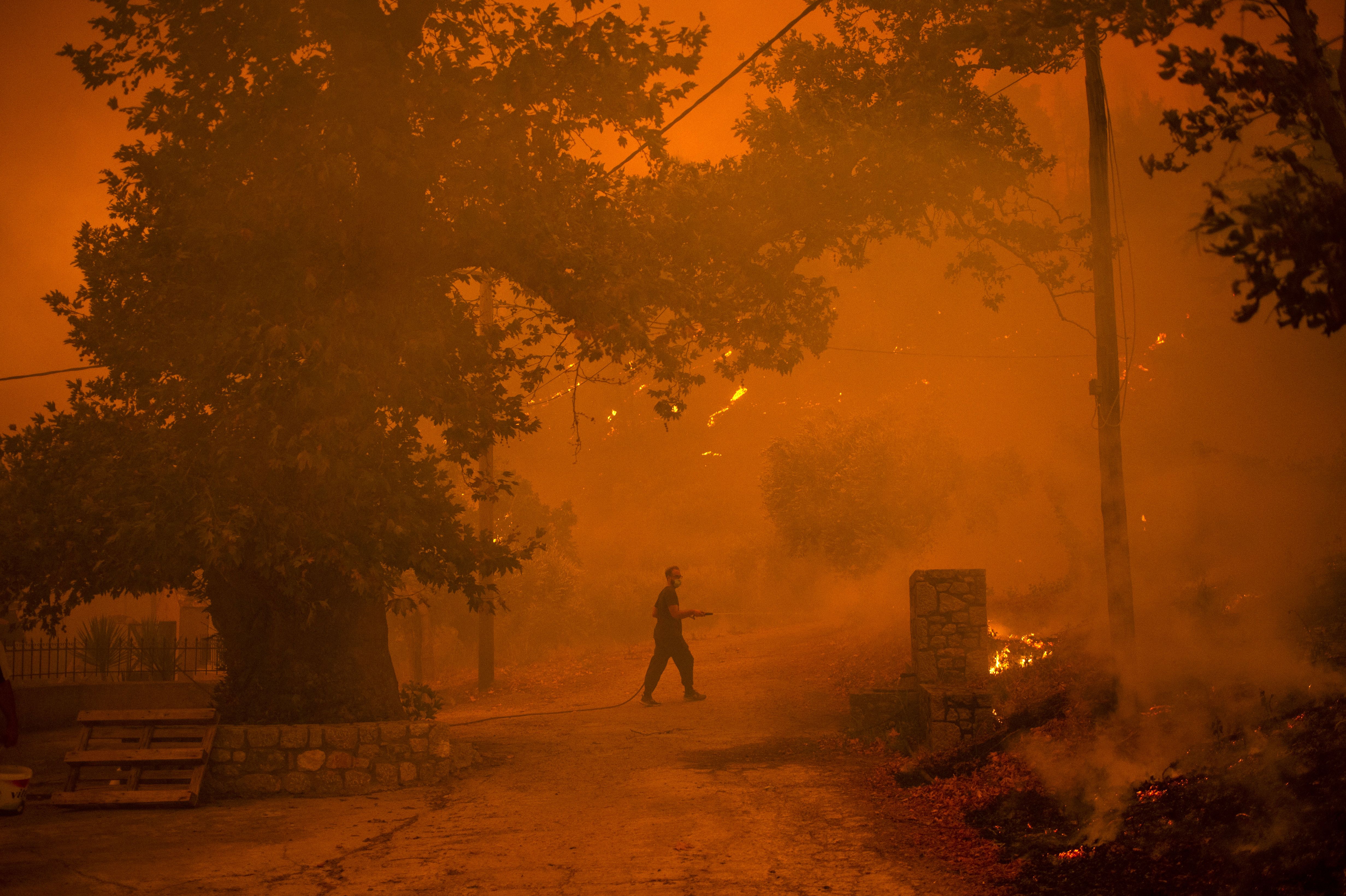 A local resident drops water as he fights a wildfire in the village of Gouves on Evia island, on 8 August, 2021.