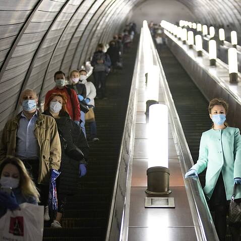 People wearing face masks and gloves to protect against the COVID-19 coronavirus observe social distancing guidelines on the subway in Moscow, Russia.