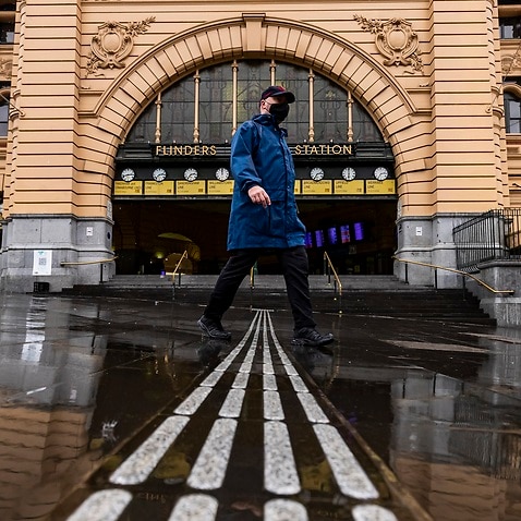 A person is seen walking past Flinders Street Station in Melbourne