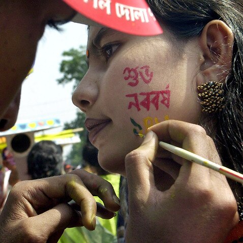 A Dhaka University student writes Happy New Year in Bengali, on the face of a fellow student during Pahela Baishakh, the first day of the Bangla New Year, in Dhaka, Bangladesh, Thursday, April 14, 2005. (AP Photo/Pavel Rahman)