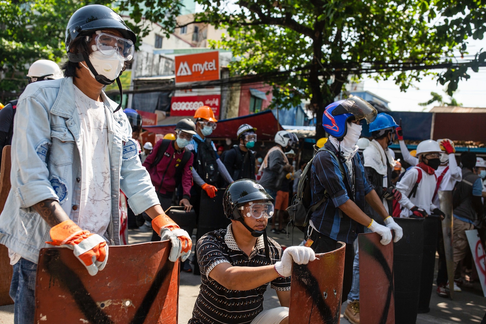 Protesters take cover behind makeshift shields during anti-coup rallies.