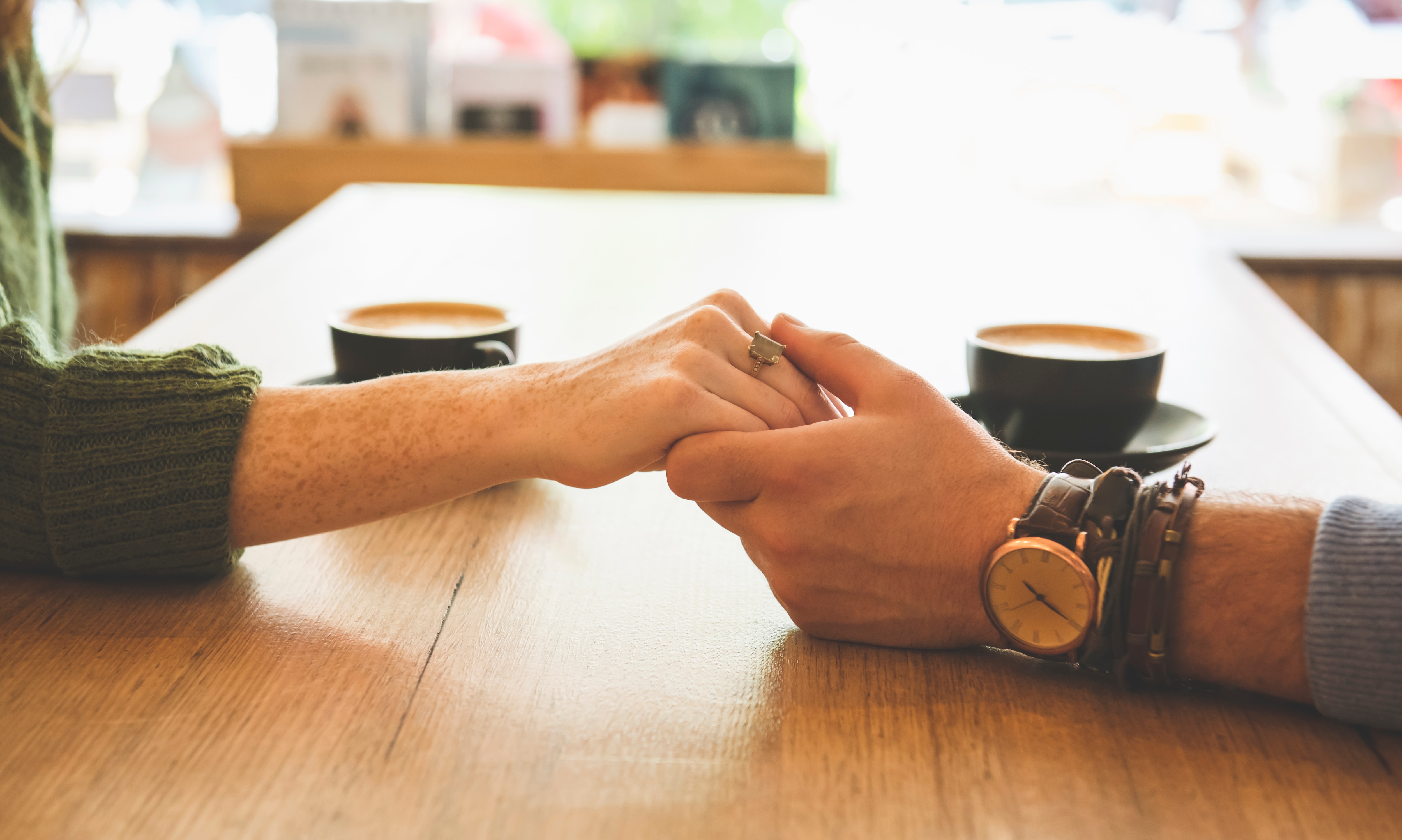 Close up of Caucasian couple holding hands in coffee shop