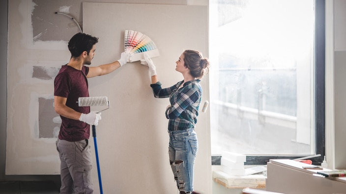 Young couple choosing the right color for their wall while renovating apartment.