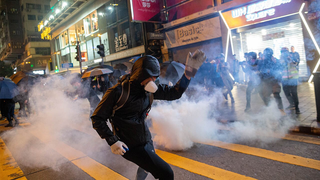 Pro-democracy protesters run from riot police firing tear gas during a rally in Tsim Sha Tsui, Hong Kong.