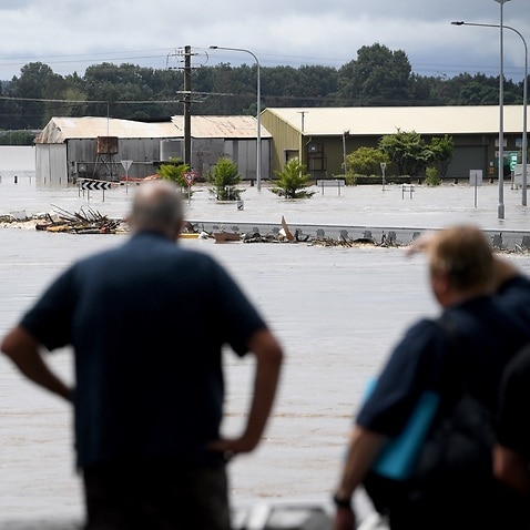 People watch on as debris carried by floodwater in the swollen Hawkesbury river in Sydney.