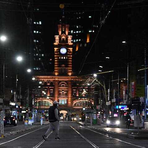 A person wearing a face mask is seen crossing a street ahead of the curfew in Melbourne, Monday, 16 August, 2021.