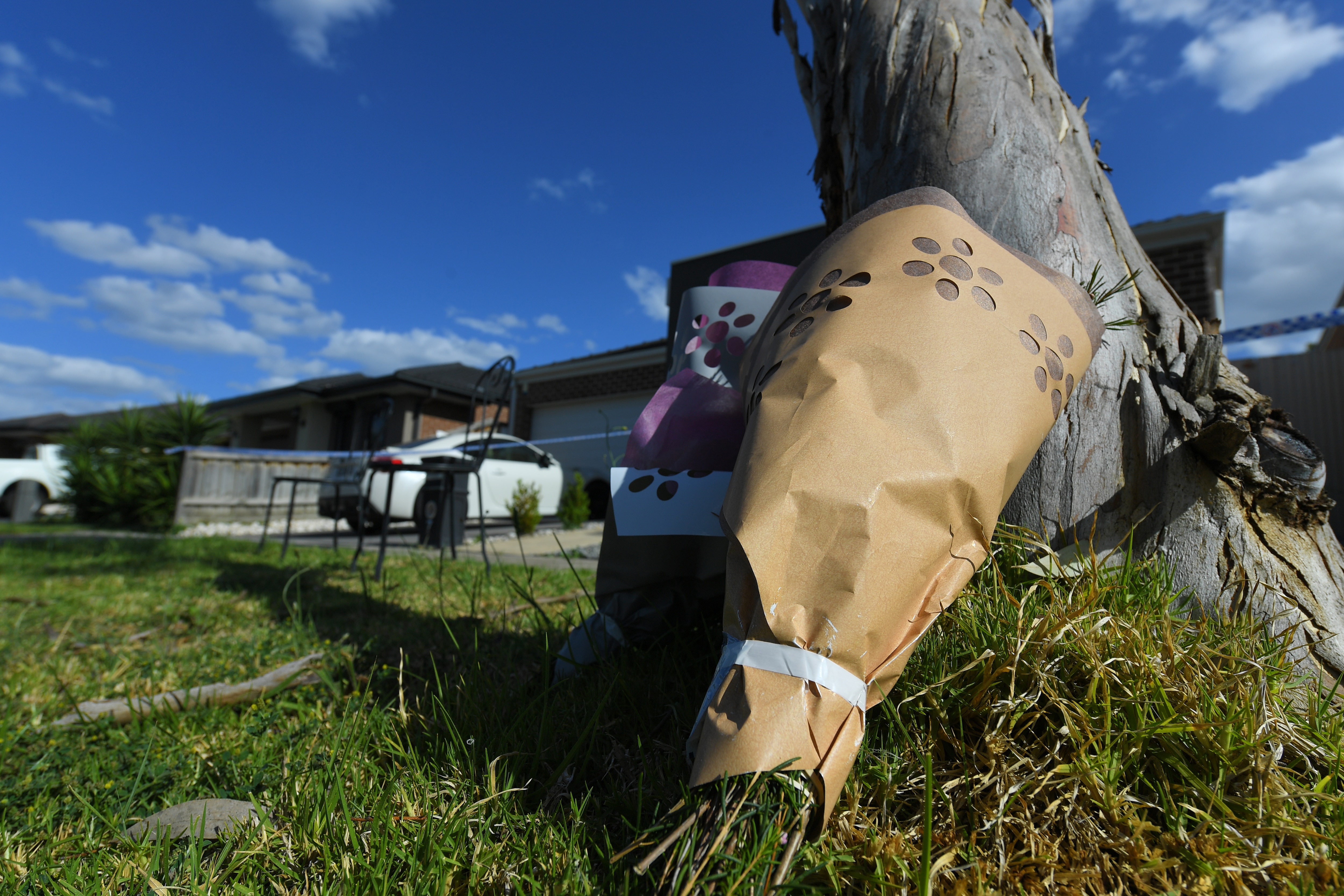 Flowers are laid against a tree outside of the scene where a woman's body was discovered in Mernda, Melbourne, on 16 November.