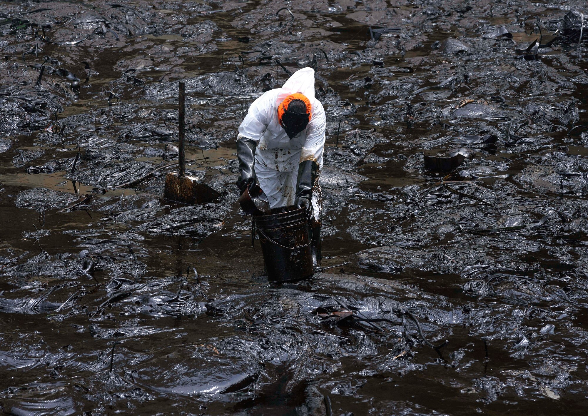A worker cleans oil from Cavero Beach in the Ventanilla district of Callao, Peru.