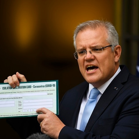 Australian Prime Minister Scott Morrison holds up a Coronavirus Isolation Declaration Card as he speaks to the media at Parliament House.