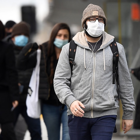 Commuters walk past Melbourne's Flinders Street Station on 23 July, 2020 on the first day of the mandatory wearing of face masks in public areas.