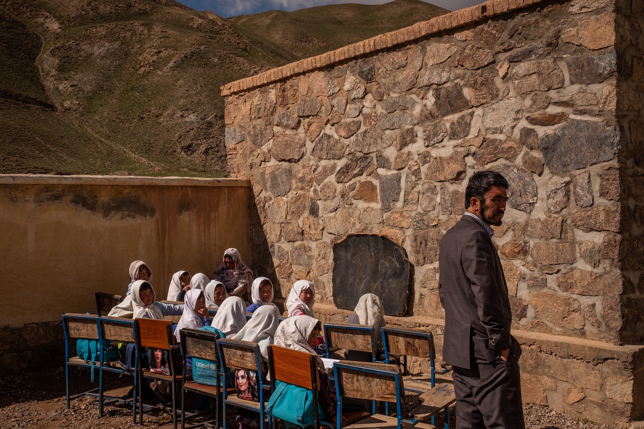Mohammad Sadiq Nasiri, the school’s principal, checking on first graders, who attend class in open air.