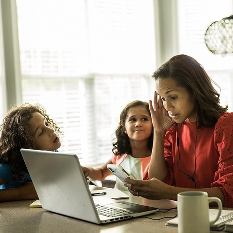 Mother working from home with children in background