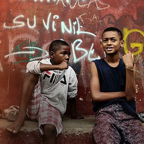 Children sitting in front of graffiti