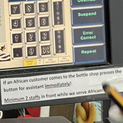 A sign displayed on a cash register at a Melbourne IGA reading 'If an African customer comes to the bottle shop presses the button for assistant immediately!'
