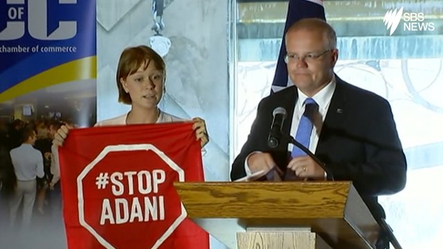 A Stop Adani protester takes to the stage where Australian Prime Minister Scott Morrison is giving an address. A Stop Adani protester takes to the stage
