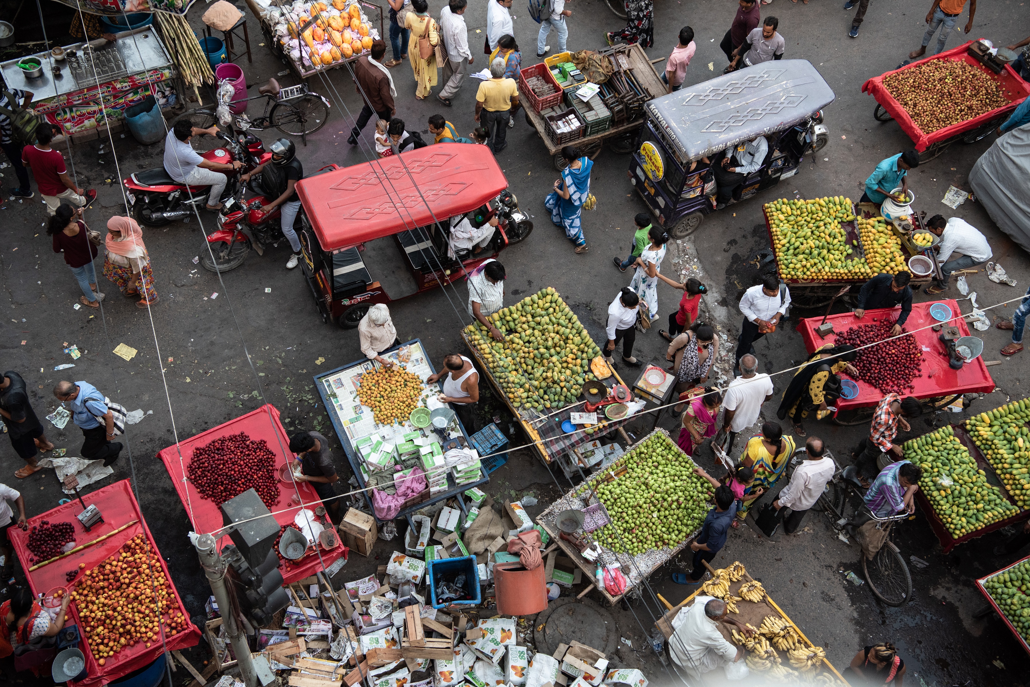 Electric rickshaws ride into a narrow lane surrounded by pedestrians and hand carts in New Delhi, July 1, 2019. (Saumya Khandelwal/The New York Times)