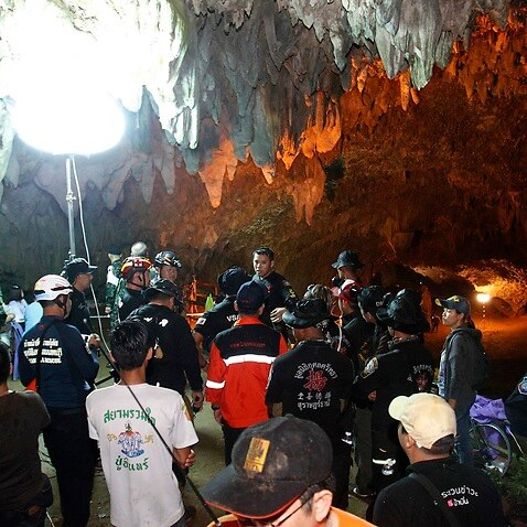 Thai rescue workers and associated officials plan a rescue operation for 12 football players and their coach outside the Tham Luang cave. 