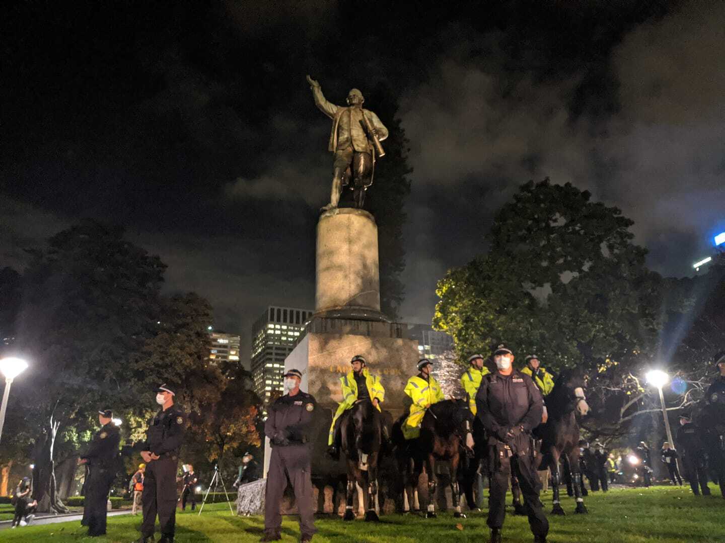 Police surround a statue of James Cook in Hyde Park during the protest.