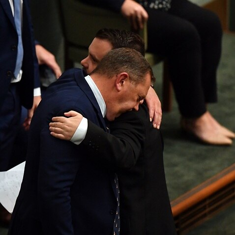 Liberal MP Phillip Thompson is hugged by colleague Gavin Pearce after speaking on veteran suicide