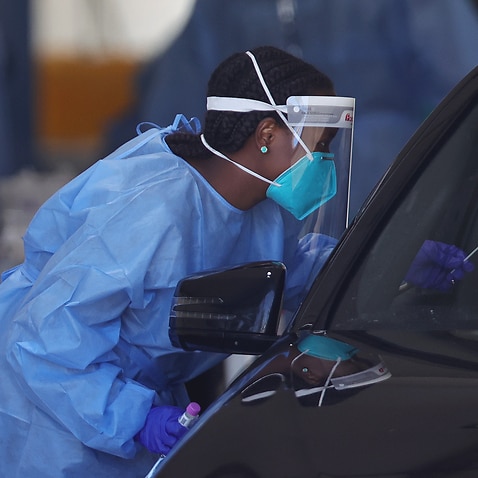 A health staff member is seen administering a PCR test at a drive-through COVID-19 testing site at Albert Park in Melbourne.