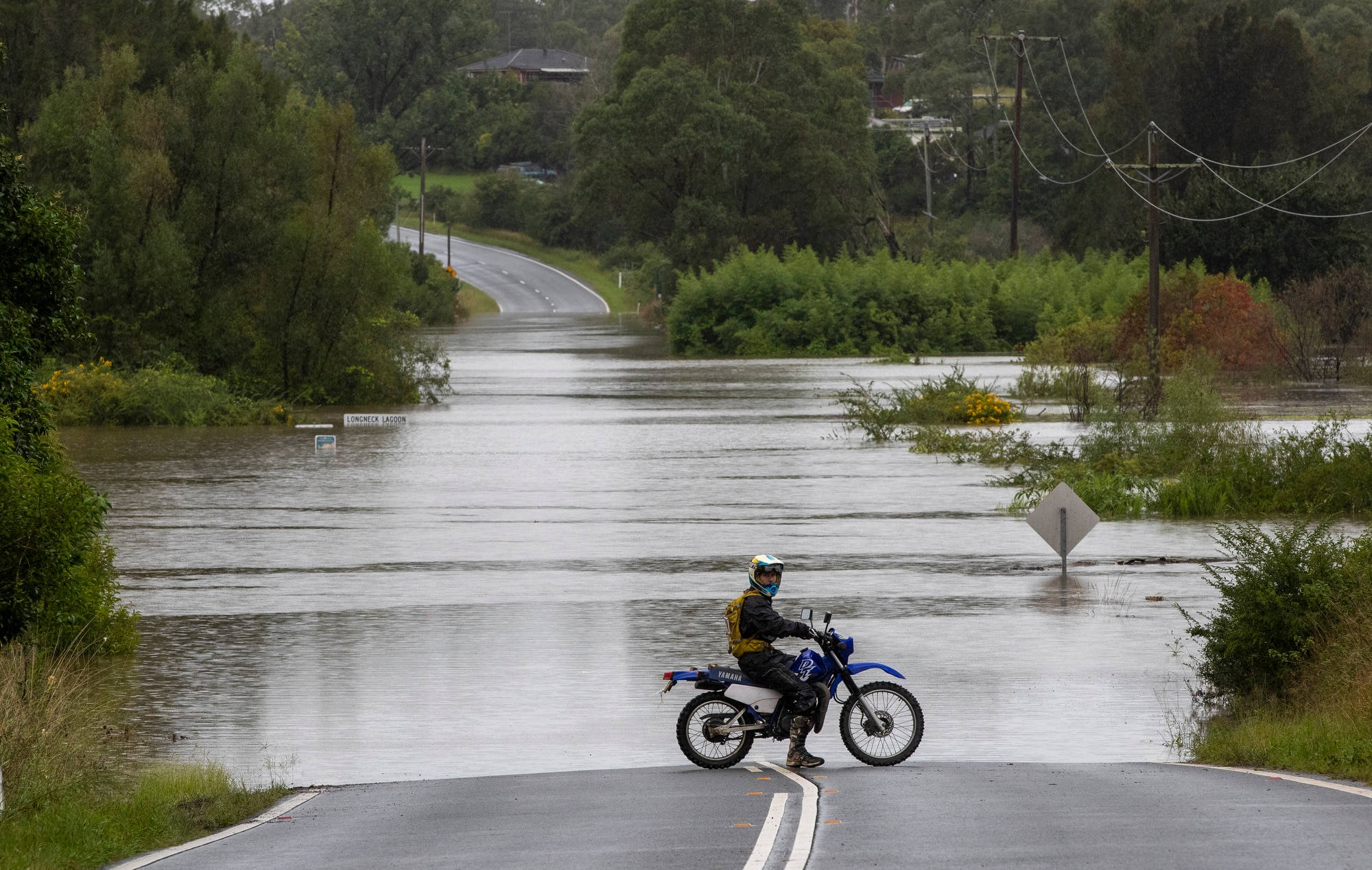A motorcyclist progress is blocked by a flooded road at Old Pitt Town, north west of Sydney.