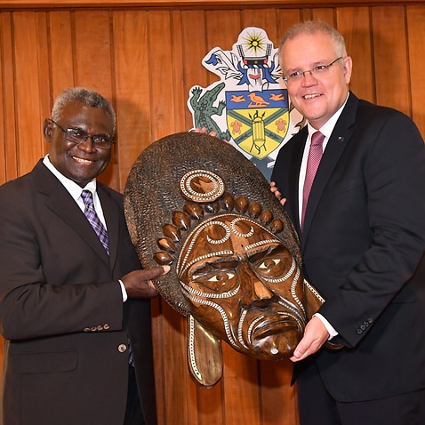 Solomon Islands Prime Minister Manasseh Sogavare (left) presents a traditional wood carving to the Australian Prime Minister Scott Morrison.