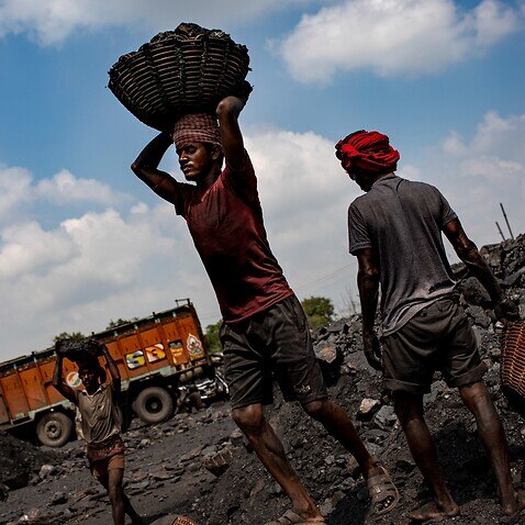 Laborers load coal onto trucks for transportation near Dhanbad, an eastern Indian city in Jharkhand state, 