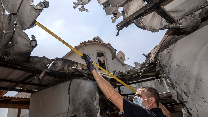 An Israeli police officer inspects the damage to a home after it was hit from a rocket fired by Palestinian militants from Gaza Strip.