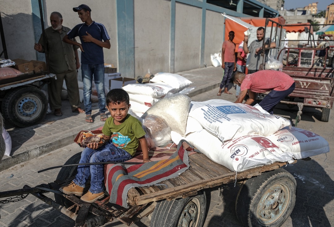 A Palestinian child sits on a cart carrying aid distributed by United Nations Relief and Works Agency for Palestine Refugees.