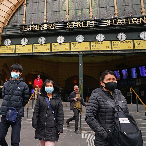 People leave Flinders Street Station while while wearing face masks (AAP).