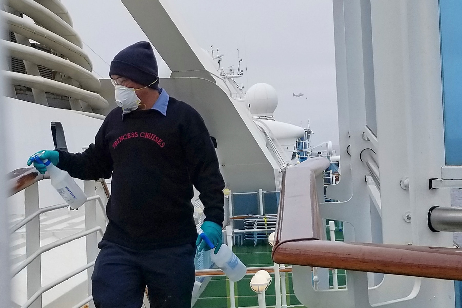 A cruise ship worker cleans a railing on the Grand Princess off the California coast