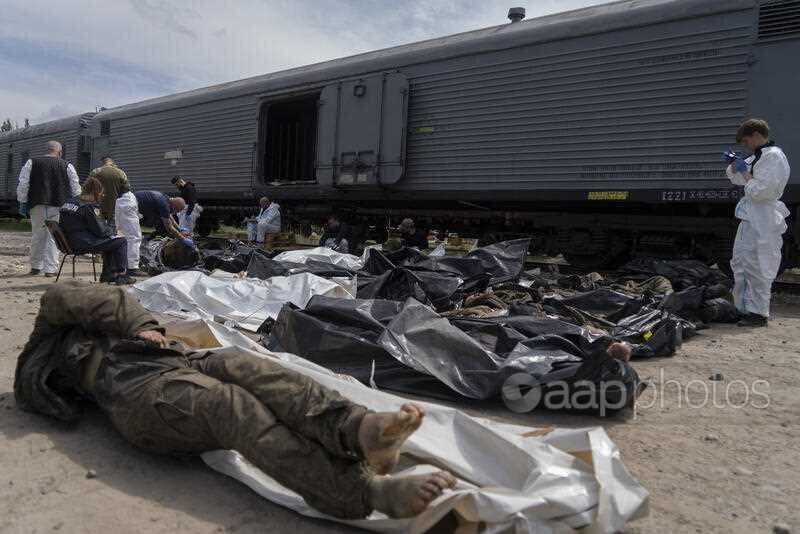 Forensic experts inspect bodies of dead Russian soldiers during an identification process in Kharkiv, east Ukraine, Saturday, May 14, 2022. The bodies of more than 41 Russian soldiers who were found after battles around Kharkiv are being stored in the ref