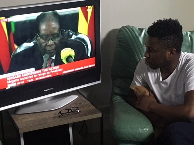 Kuda Mangoma watching the coverage of Mugabe's resignation (SBS News)