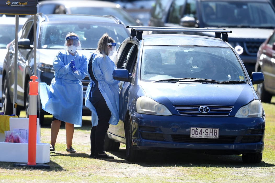 Health workers swab members of the public at a pop-up COVID-19 testing station at Indooroopilly State High School in Brisbane