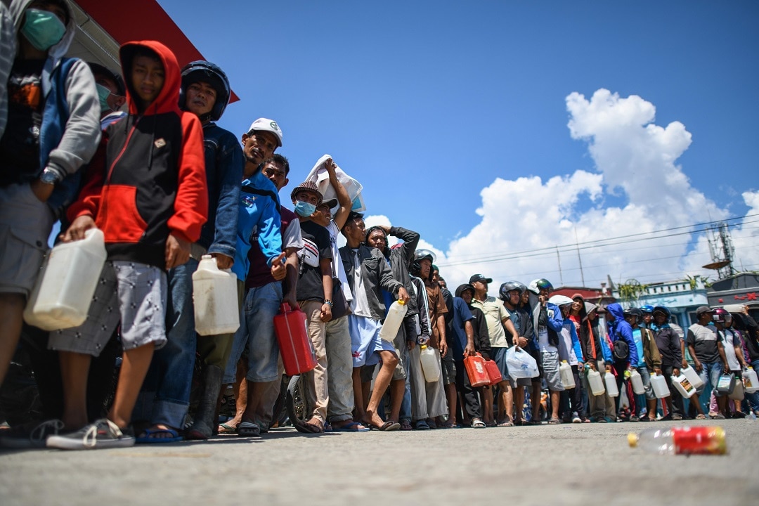 Survivors line up at a service station to get gasoline in Palu.