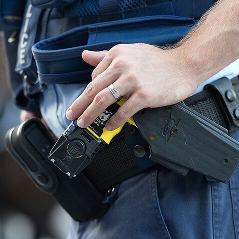 Stock photograph of a Queensland Police Officer with his hand on a Taser
