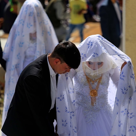 epa09838083 Grooms walk with their brides during a mass wedding ceremony in Kabul, Afghanistan, 20 March 2022.  Some 60 couples got married in a mass wedding ceremony organized by a local philanthropists.  EPA/STRINGER