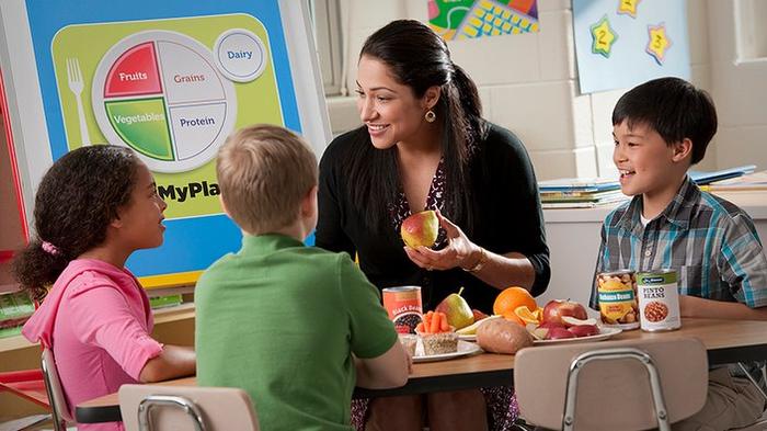 Image of a teacher with three young children discussing nutrition
