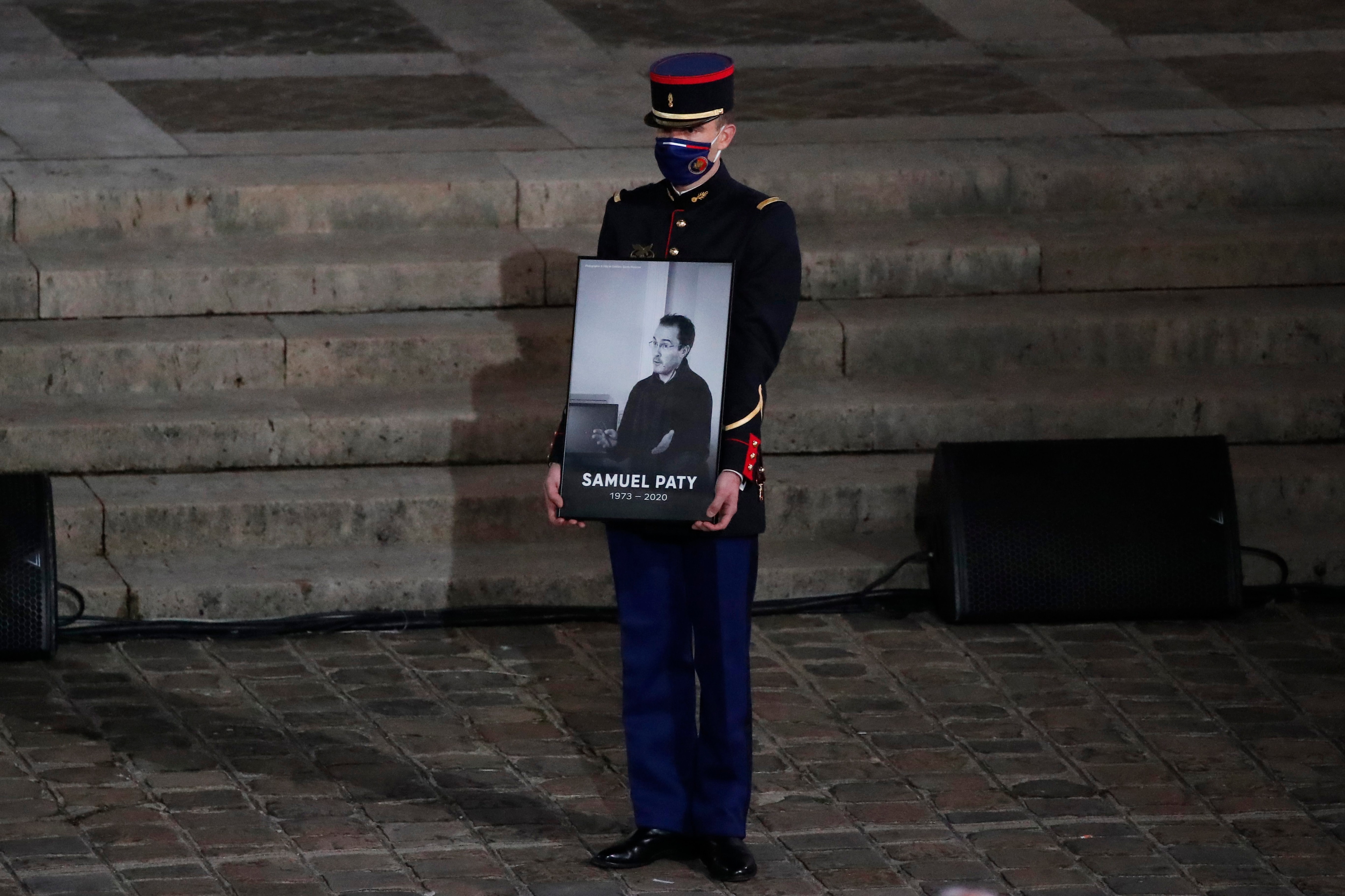  A Republican Guard holds a portrait of Samuel Paty in the courtyard of the Sorbonne university during a national memorial event, in Paris.