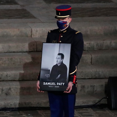  A Republican Guard holds a portrait of Samuel Paty in the courtyard of the Sorbonne university during a national memorial event, in Paris.