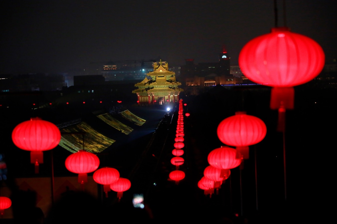 In this Tuesday, Feb. 19, 2019, photo, lanterns is decorated near a Turret of the Forbidden City projected with lights for the Lantern Festival in Beijing.