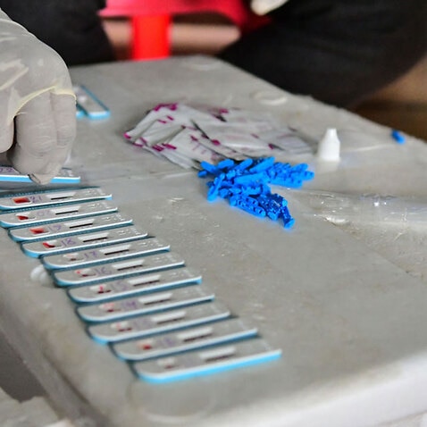 A health worker collects blood samples for HIV testing.