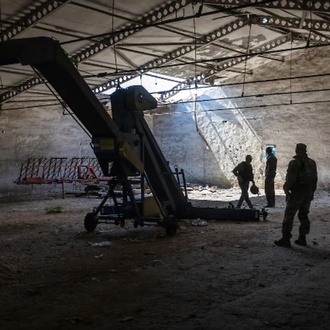 Local government officials and a Ukrainian soldier inspect a grain warehouse shelled by Russian forces near the frontlines of Kherson , Ukraine