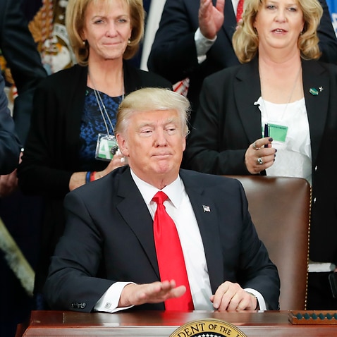 President Donald Trump taps on the table after signing an executive order for immigration actions and  to build border wall, Wednesday, Jan. 25, 2017.