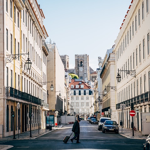 An elderly man crosses a deserted street in Lisbon.