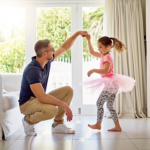 Happy father and daughter dancing together at home 