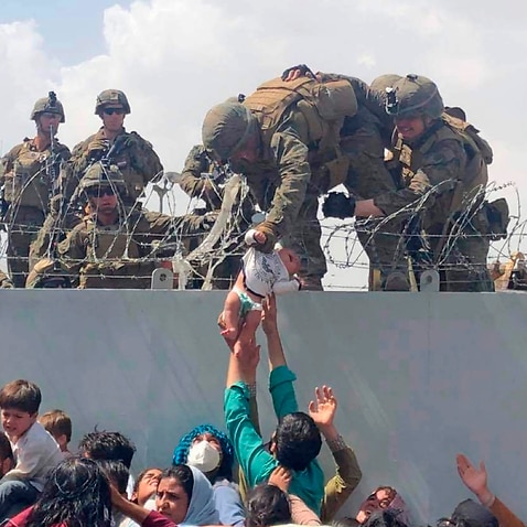 A baby being lifted across a wall at Kabul Airport in Afghanistan by US soldiers. 