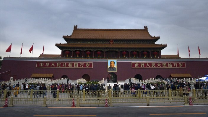 Visitors stand outside the Tiananmen Gate next to Tiananmen Square in Beijing
