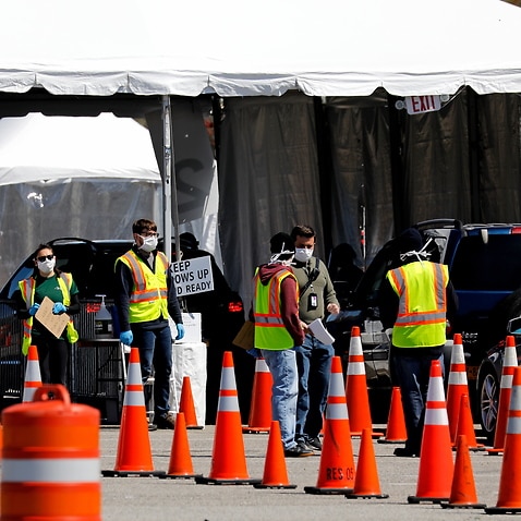 Workers direct people queueing up in theirs cars waiting to be tested for coronavirus COVID-19 at the drive-in test site in New York.