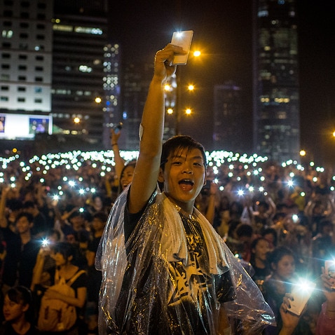 Demonstranten singen Lieder und schwenken ihre Handys in die Luft, nachdem 2019 vor dem Regierungskomplex von Hongkong ein gewaltiges Gewitter überkam.